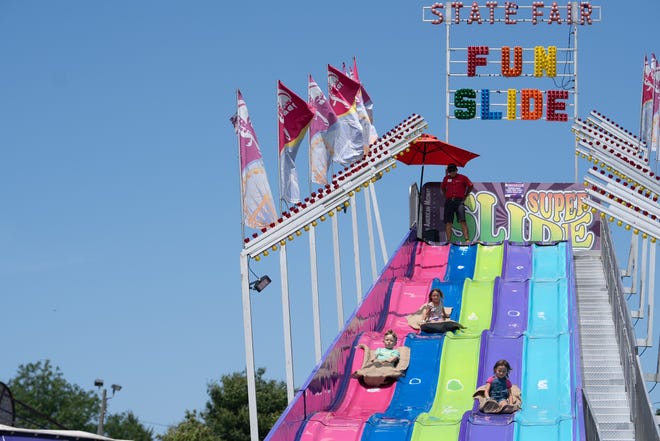 Deaglan Gluff, 5, Jade McGabe, 4 and Jaylin McGabe, 6, ride the fun slide Friday, July 28, 2023, at the Indiana State Fair in Indianapolis.